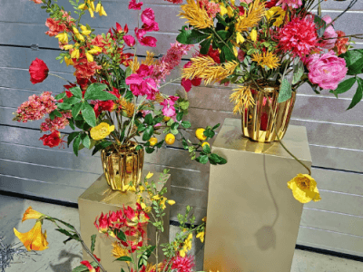 Kunstbloemen in gouden vazen op sokkels